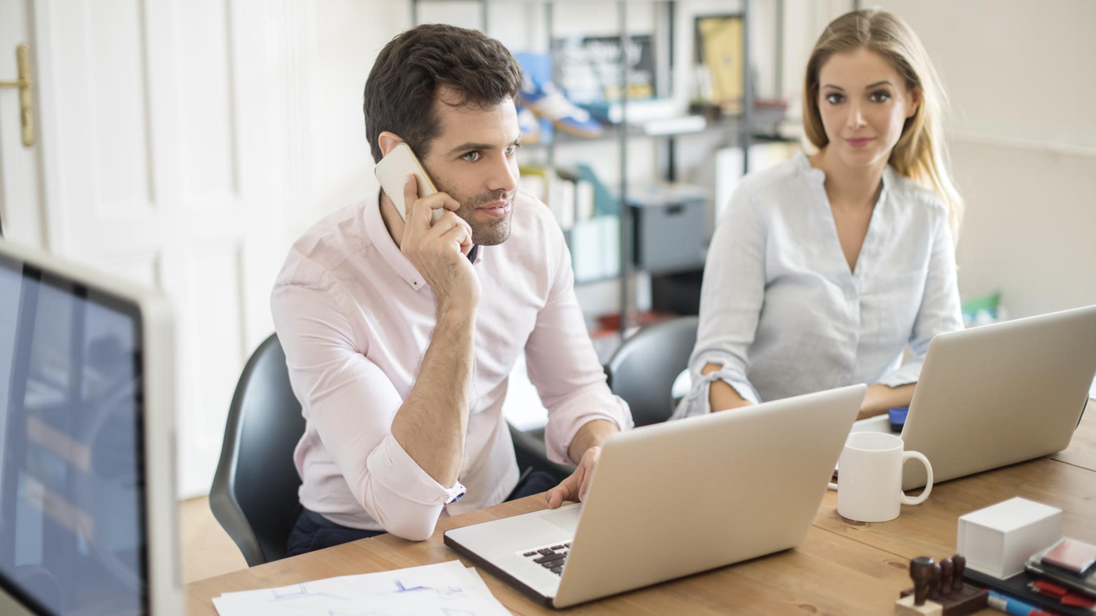 Two colleagues evaluating a new phone system together at an office desk