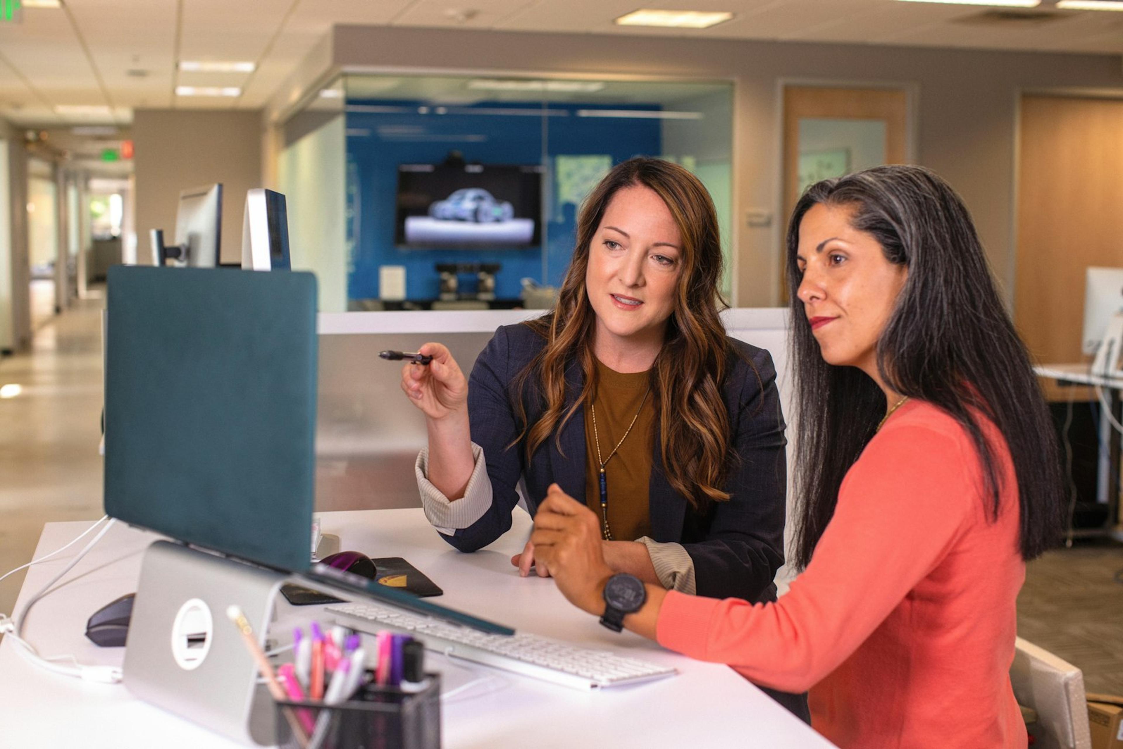 Two colleagues reviewing a customer complaint record on a computer