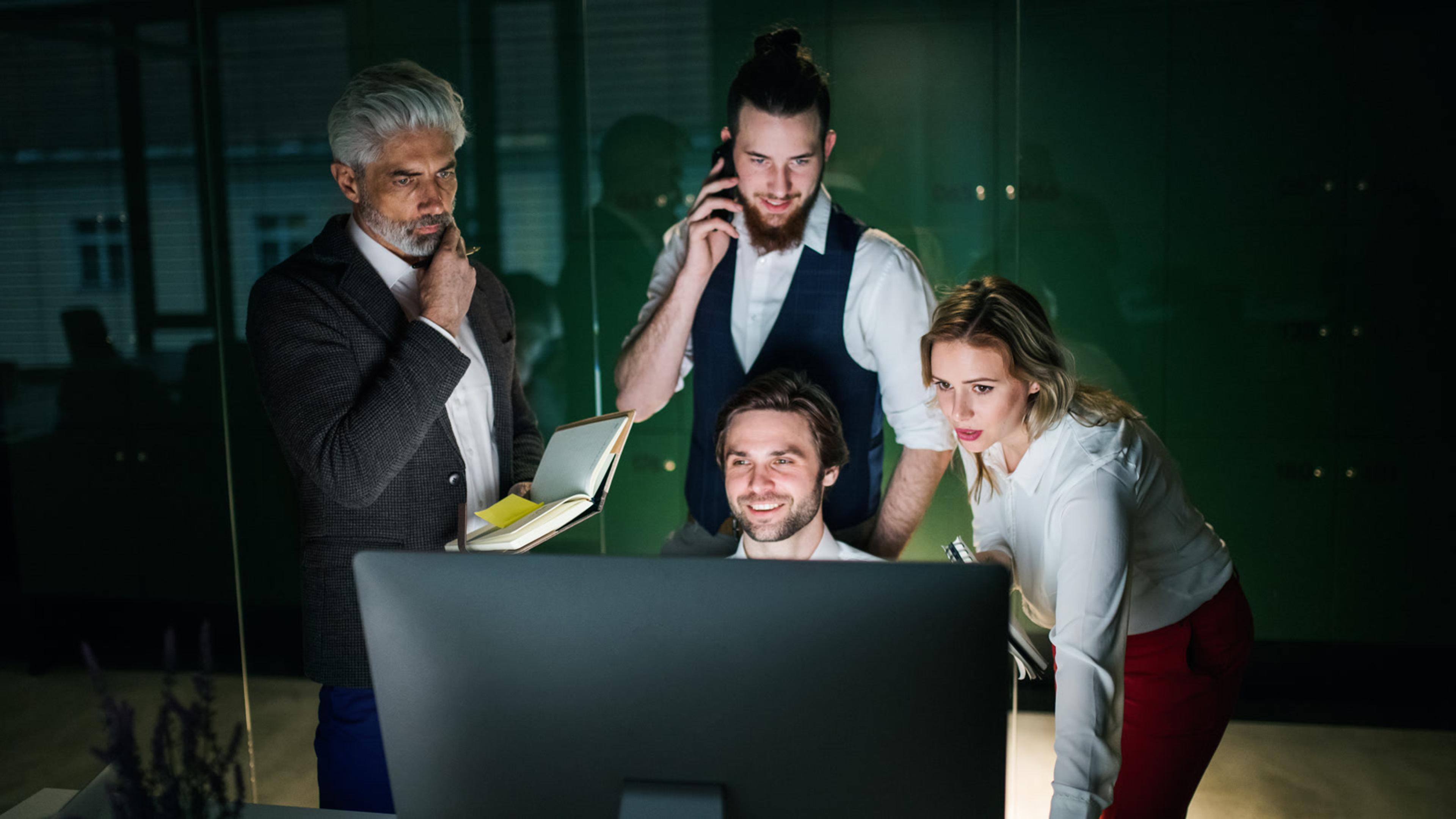 Business team collaborating at a computer while deciding SIP trunk vs cloud PBX