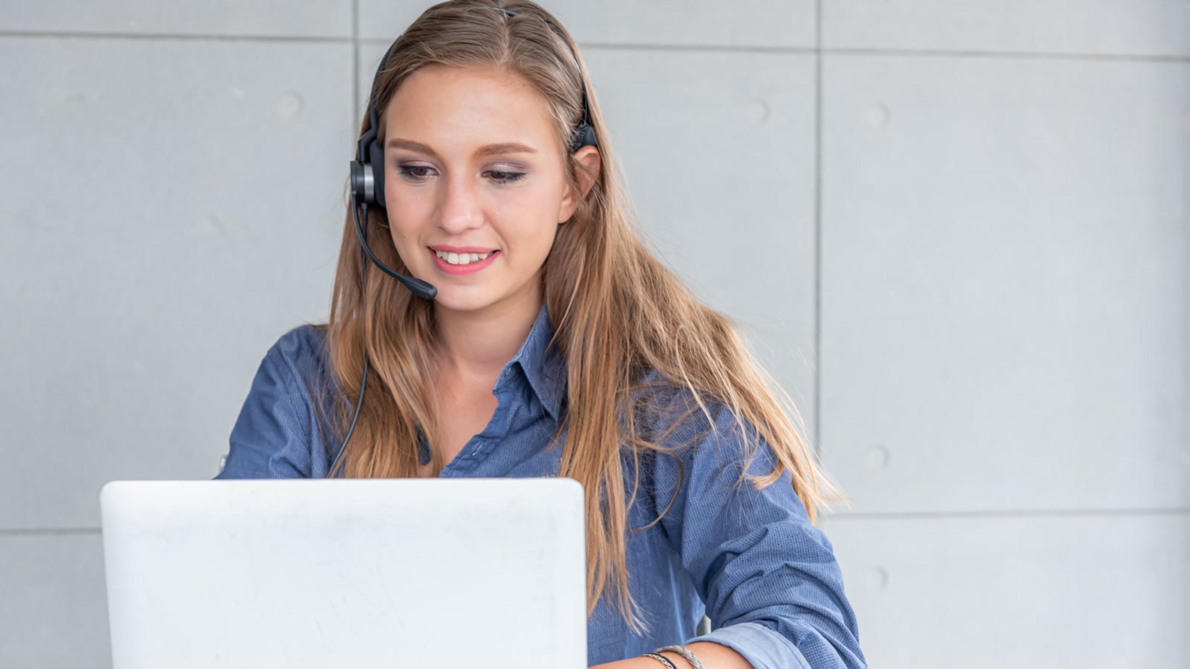 Woman with headset using a laptop softphone after cloud PBX migration