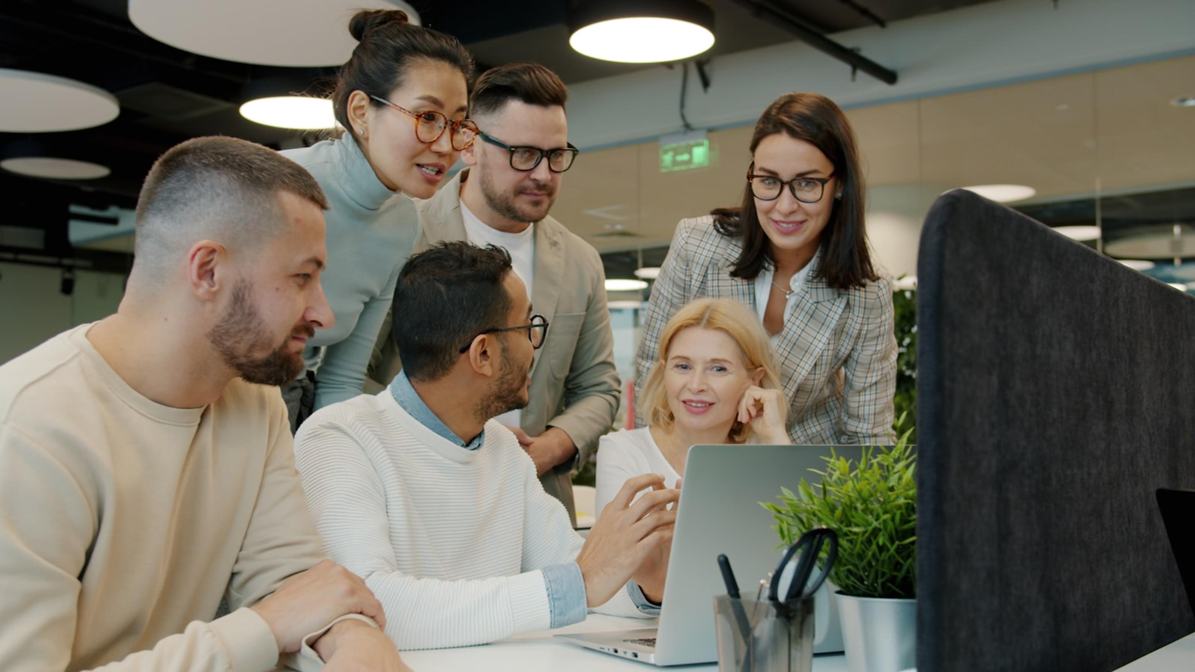 Service team collaborating around a laptop during a contact centre pilot