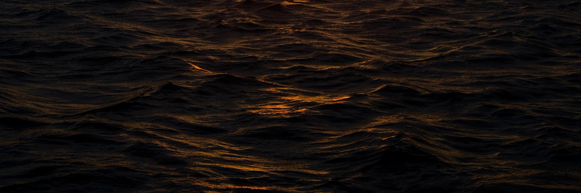 Golden sunset light reflecting on dark ocean waves