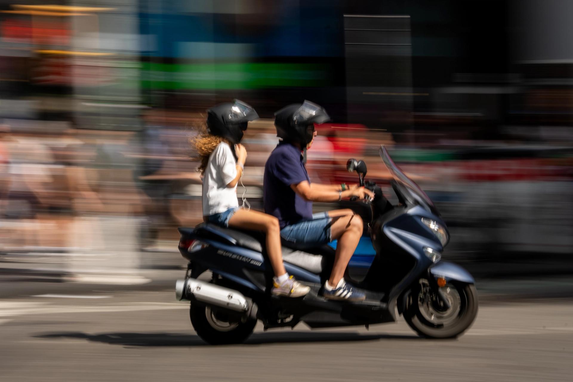 Couple on a scooter held sharp by a pan while the street blurs past