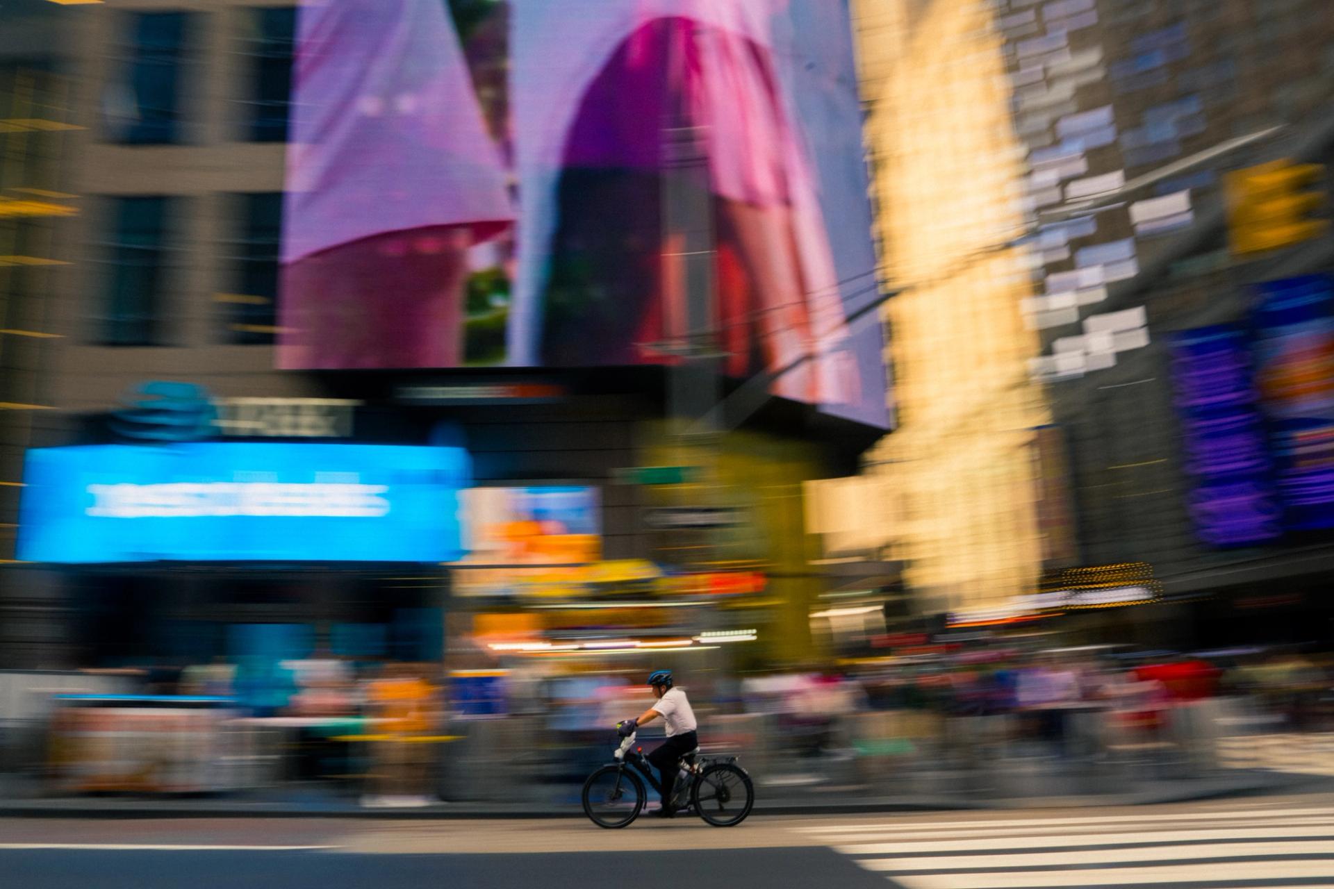 Cyclist panned in front of blurred Times Square billboards