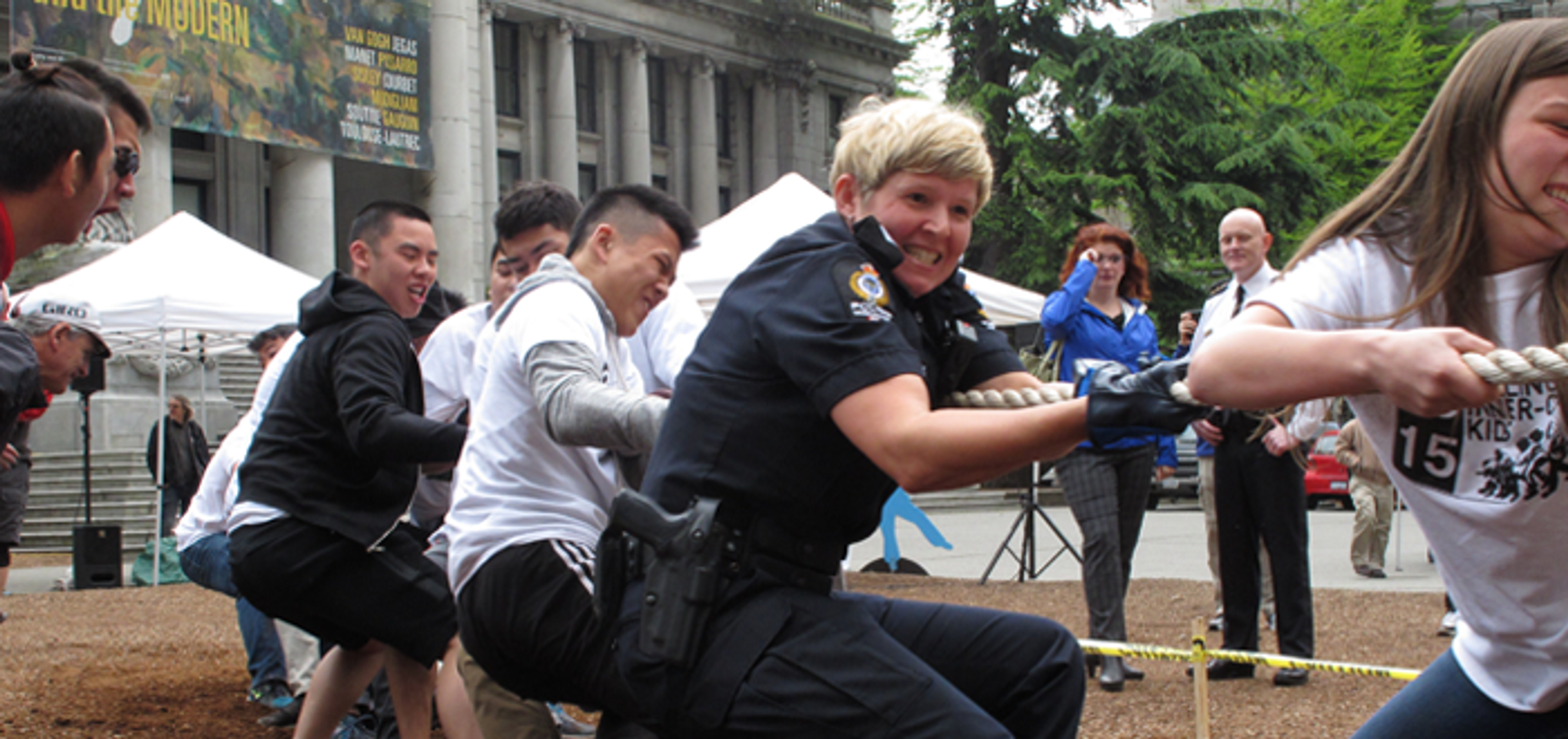 Poster for Inner City Kids Week 2016, over a photo of students and officers pulling on the rope