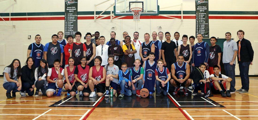 A Night Hoops team photo in a school gym, players and coaches lined up along the baseline