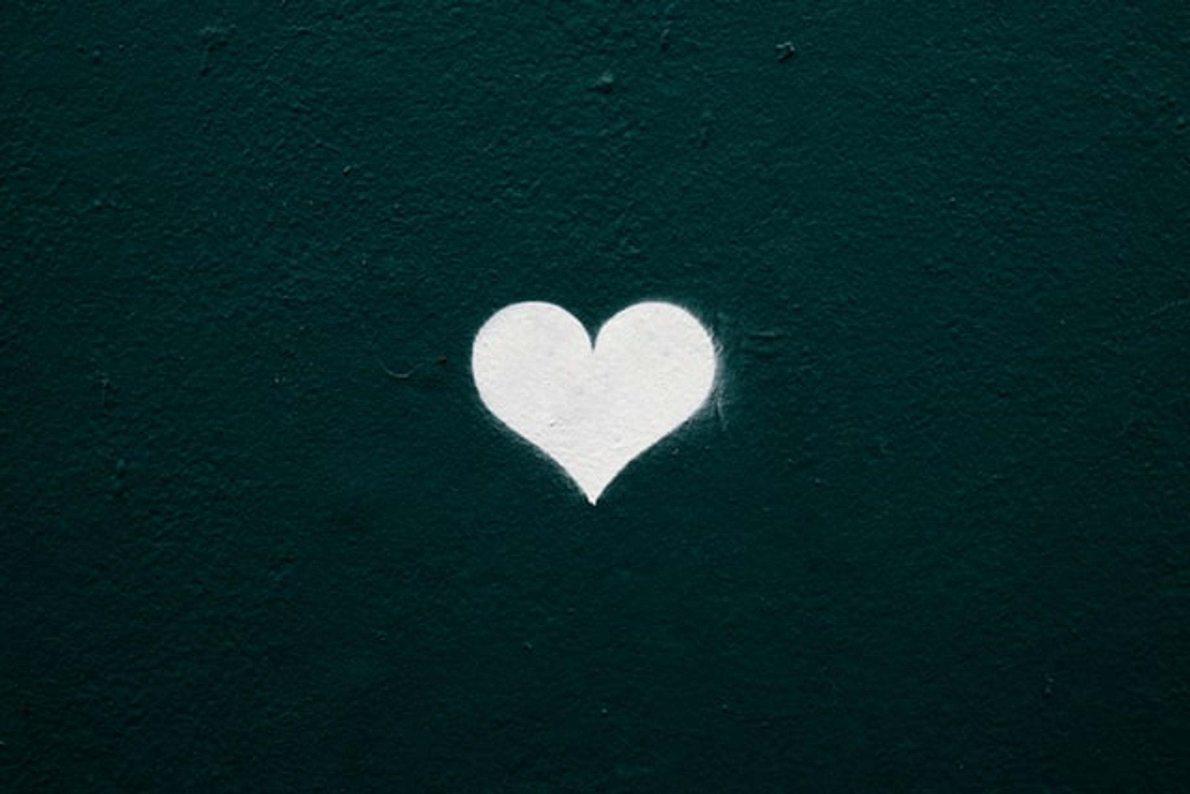 A white heart shape on a dark green textured wall
