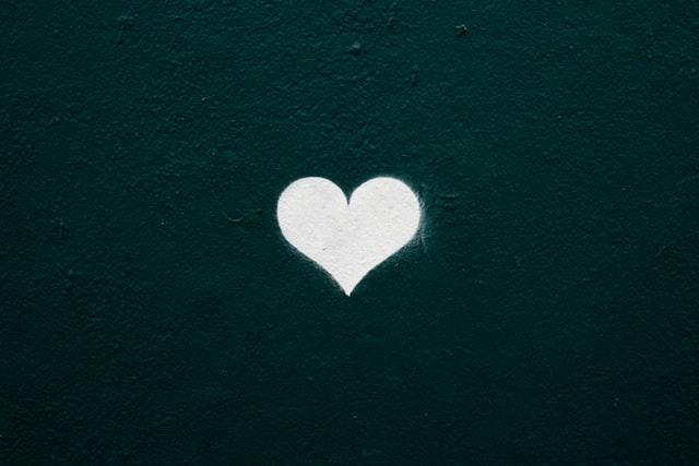 A white heart shape on a dark green textured wall