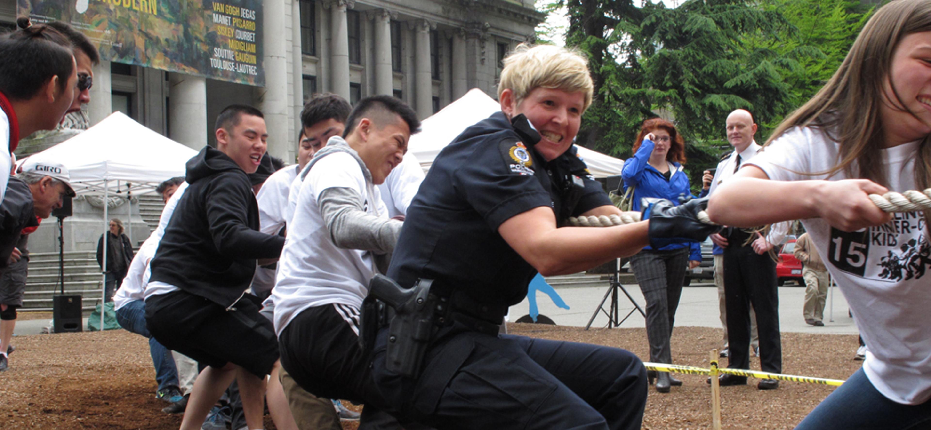 Students and Vancouver Police officers straining side by side on the tug of war rope