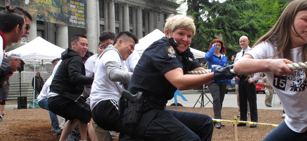 Students and Vancouver Police officers straining side by side on the tug of war rope