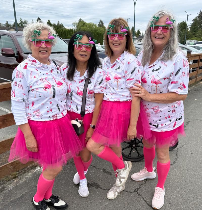 Four players in flamingo-print shirts, pink tutus, pink knee socks and palm-tree sunglasses pose in the parking lot.