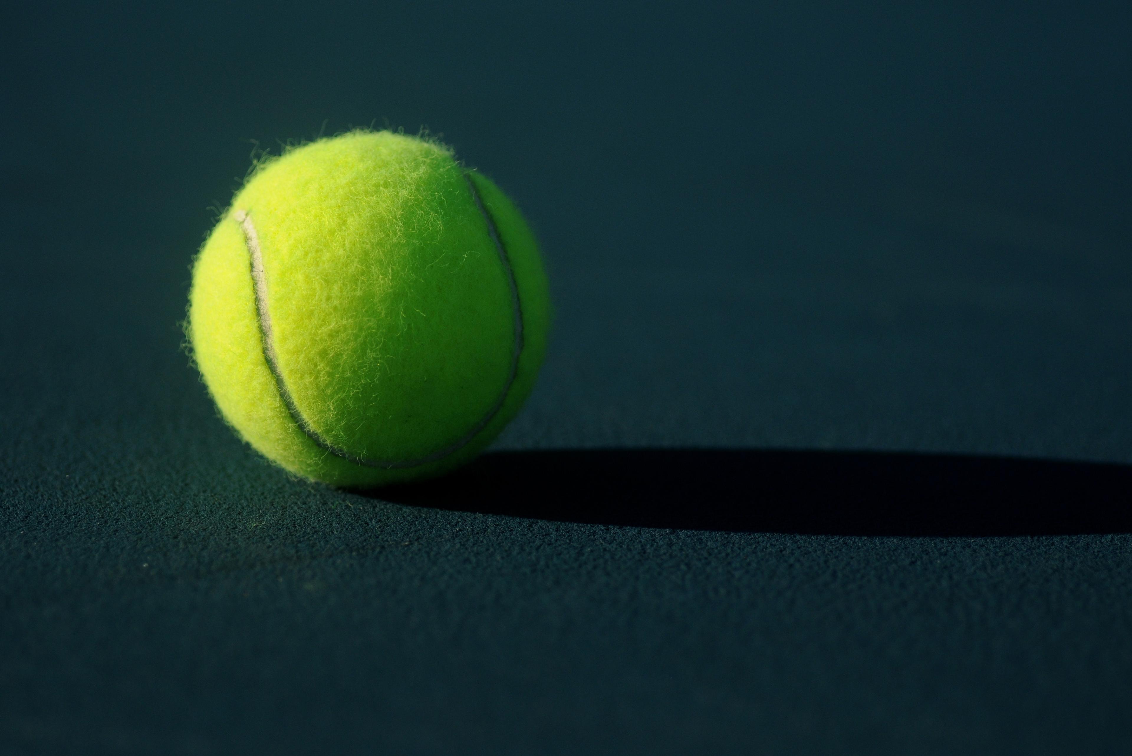 A tennis ball on a dark court surface