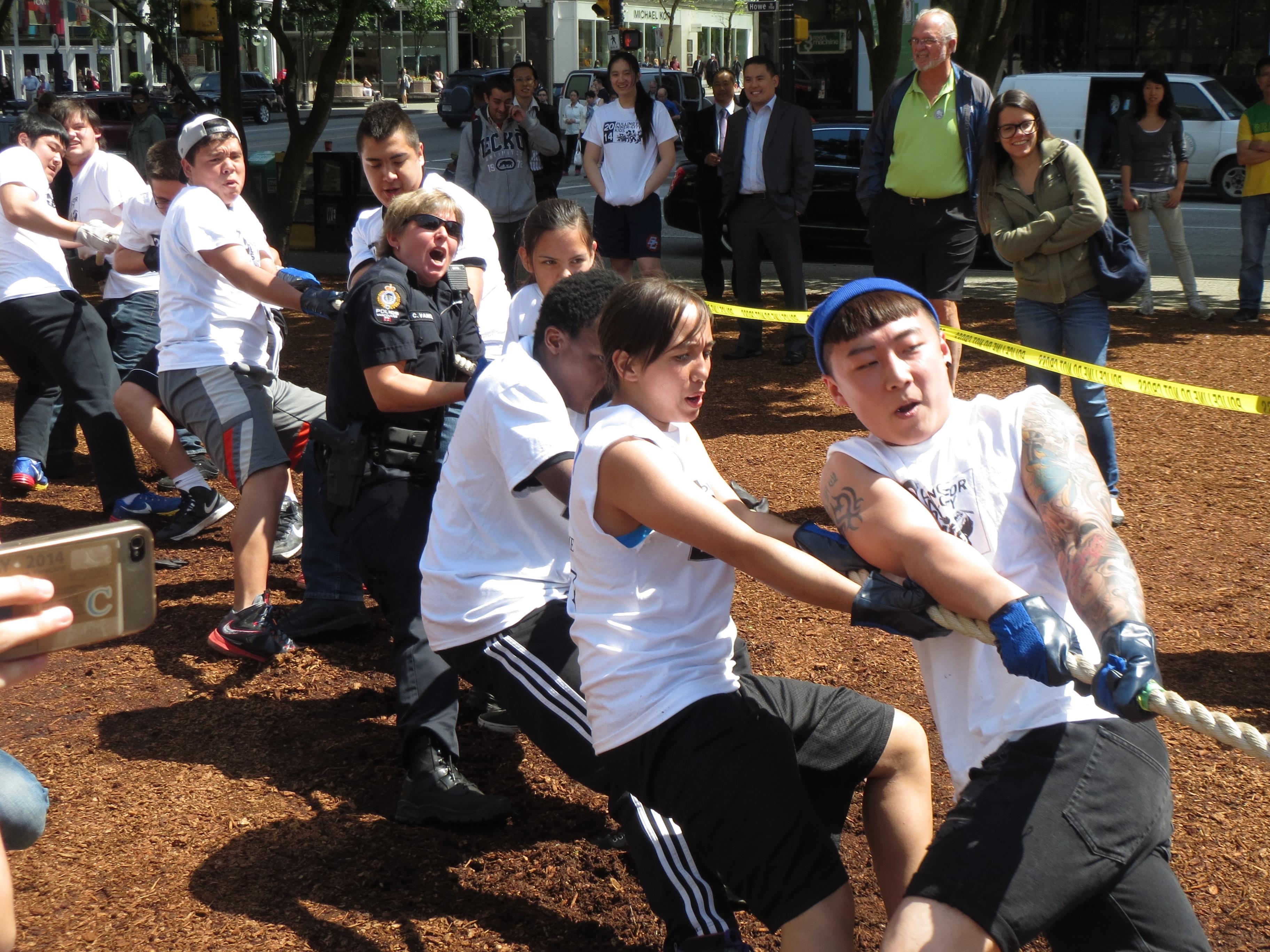 Students in white CLICK T-shirts heaving on the tug of war rope on the bark mulch