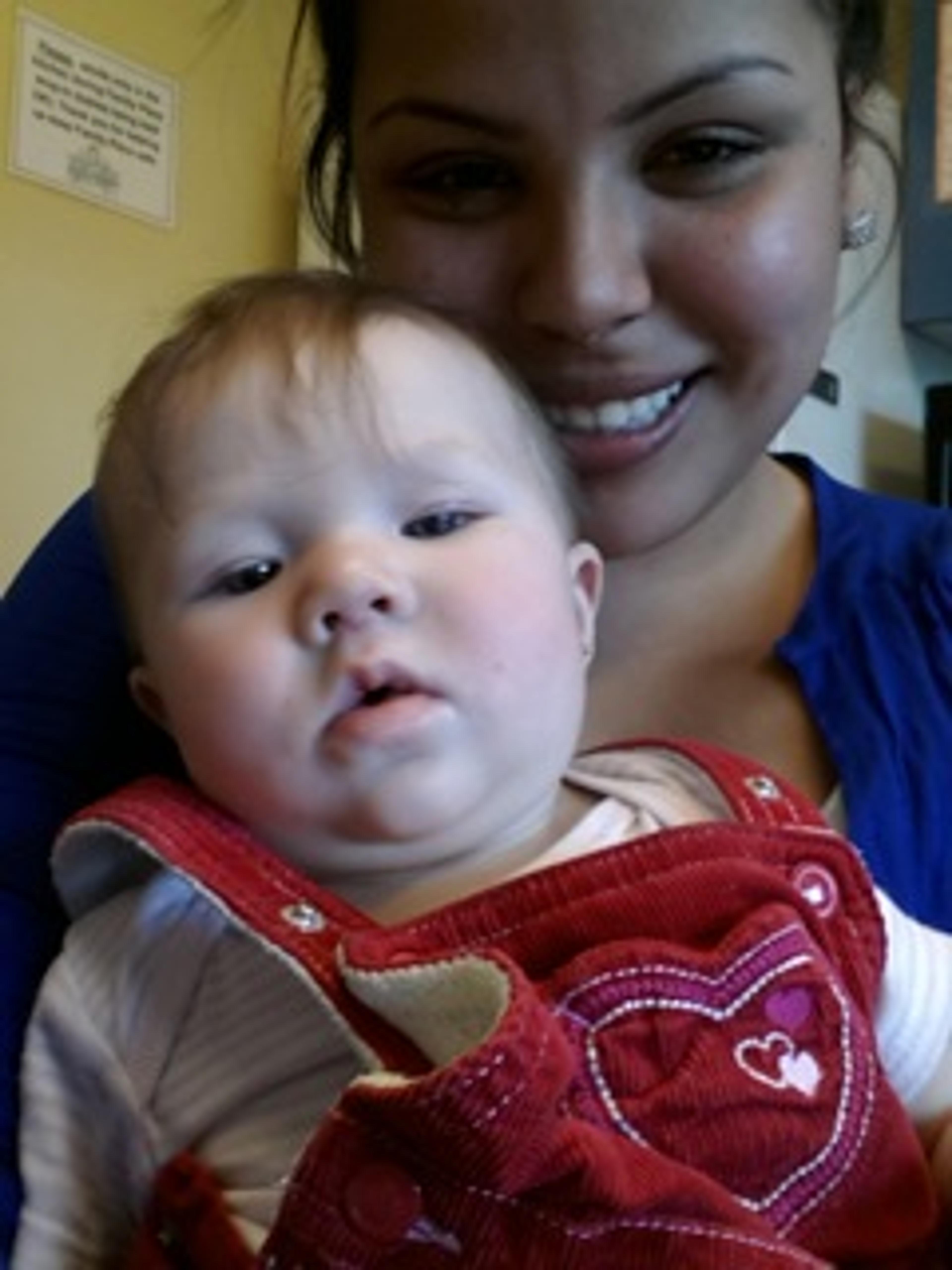 A baby in a red patterned outfit, held close
