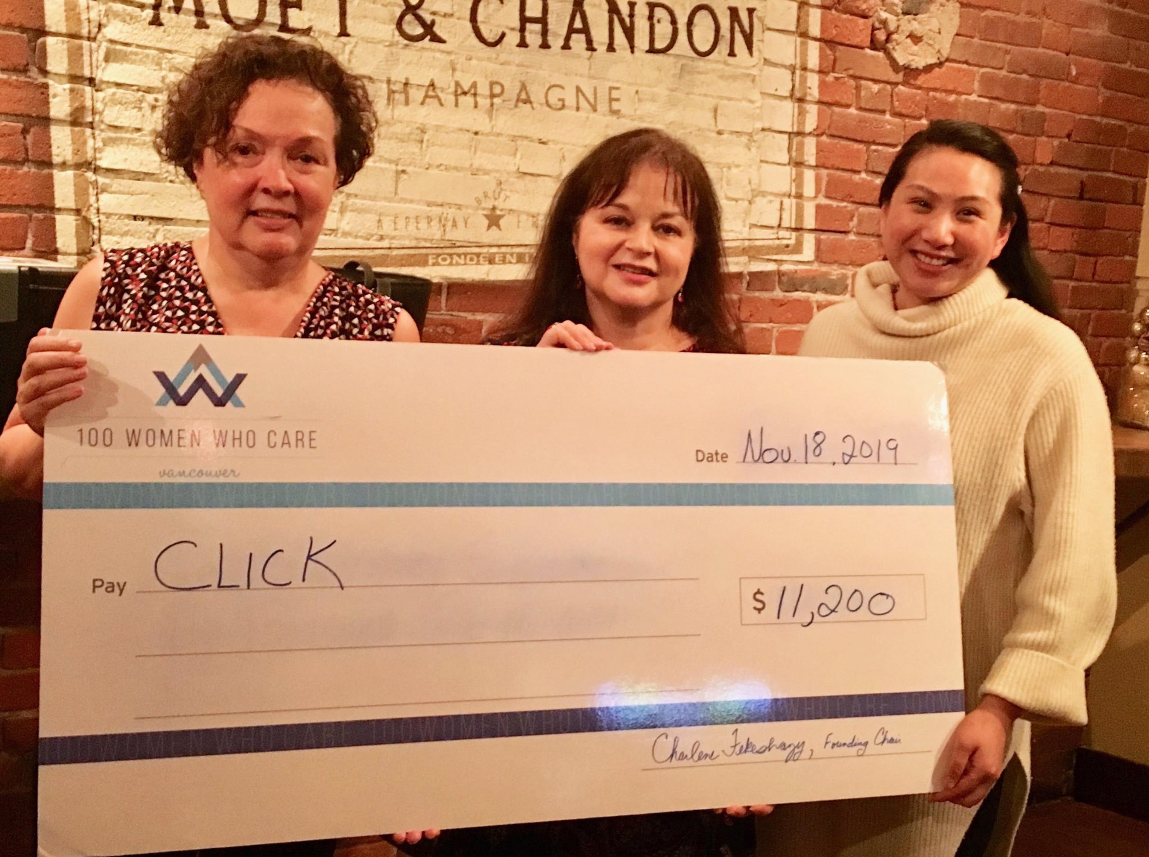Three members of 100 Women Who Care Vancouver presenting an $11,200 cheque to CLICK