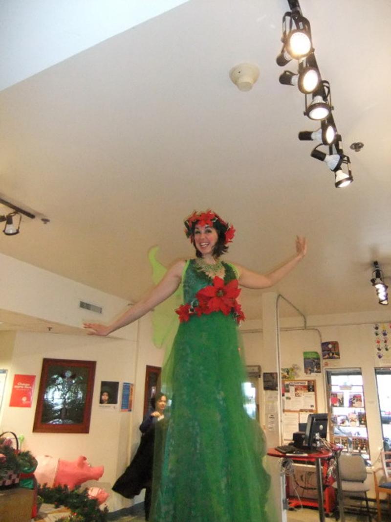 A stilt walker in a red and green costume towering over the room