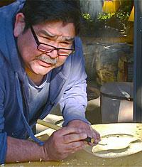Haida artist Alvin Adkins at his bench, working on a silver piece