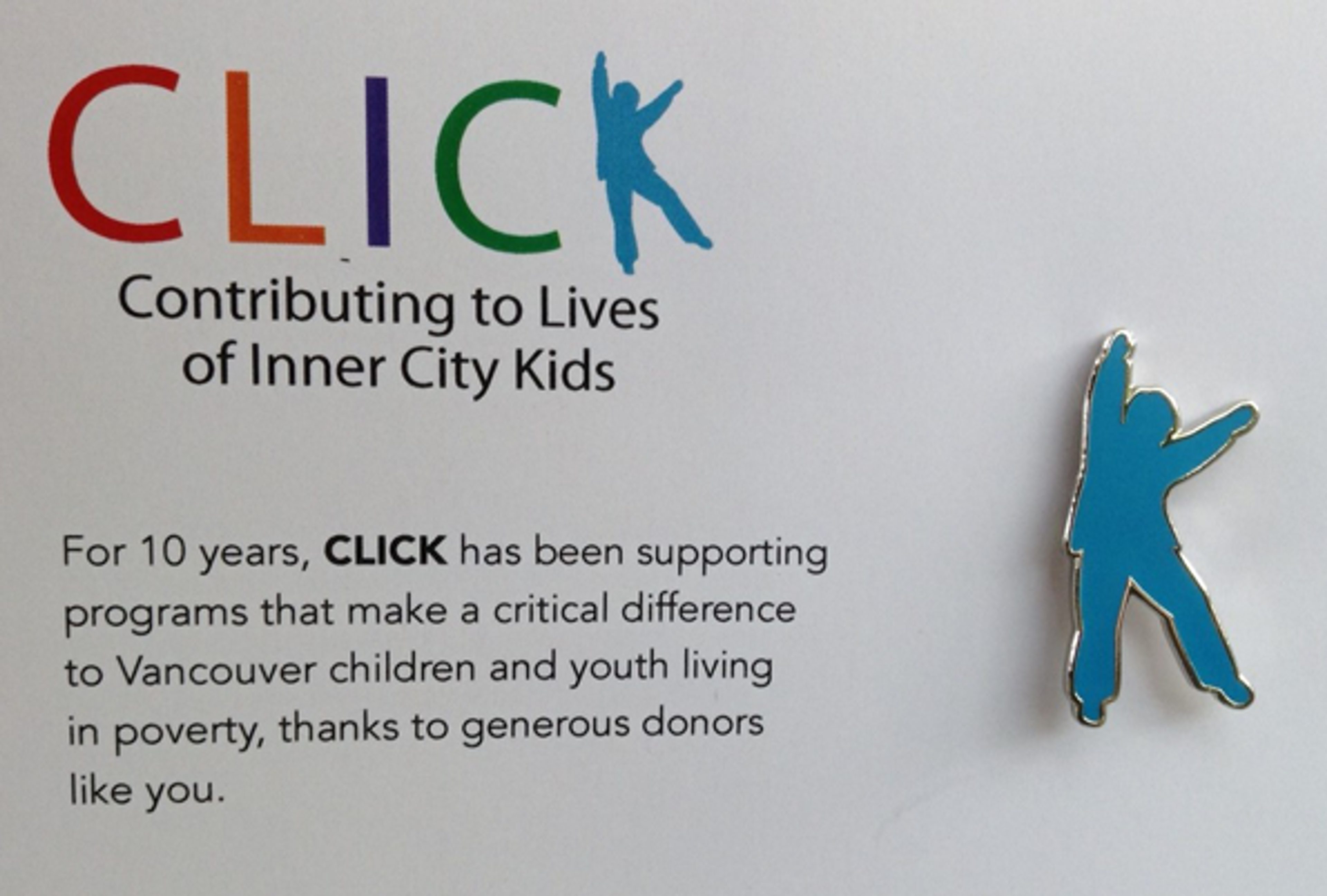 A blue enamel lapel pin in the shape of CLICK's Blue Boy figure, beside the CLICK logo