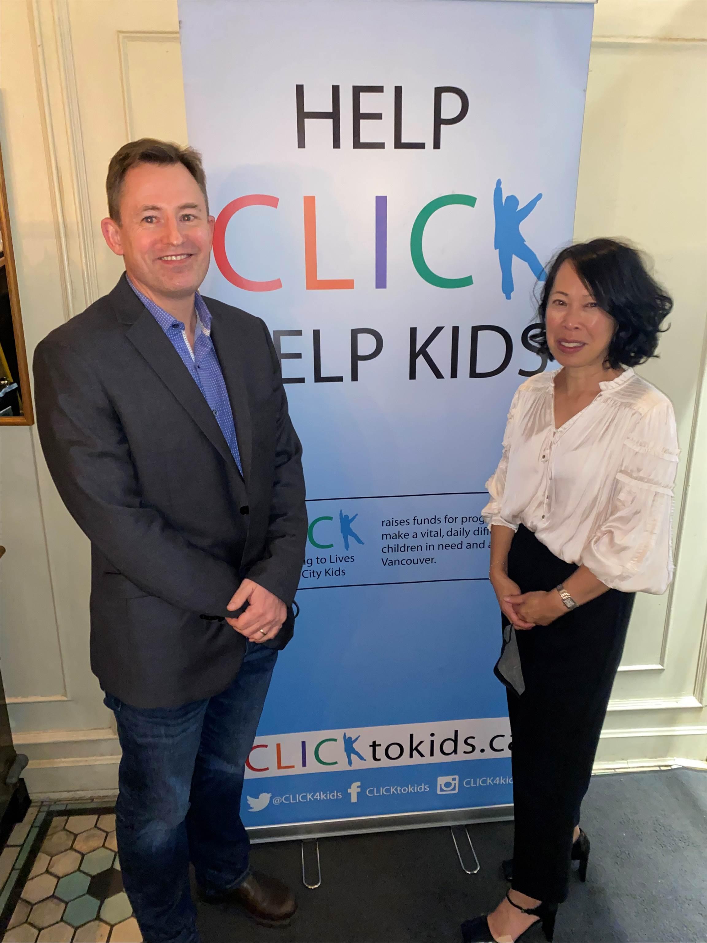 Two guests in front of the Help CLICK Help Kids banner at Café Medina