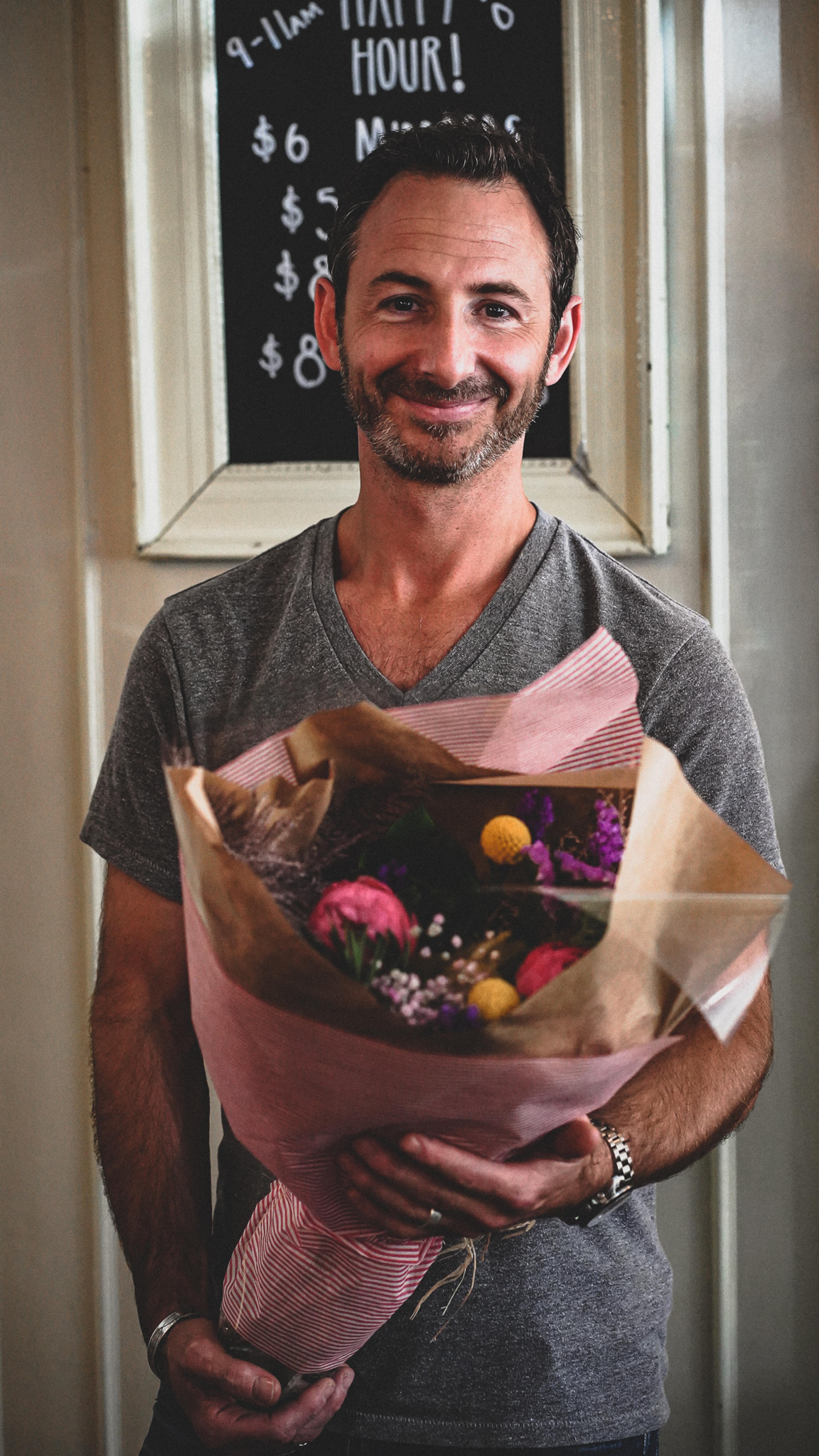 Robbie Kane, owner of Café Medina, holding a bouquet of flowers