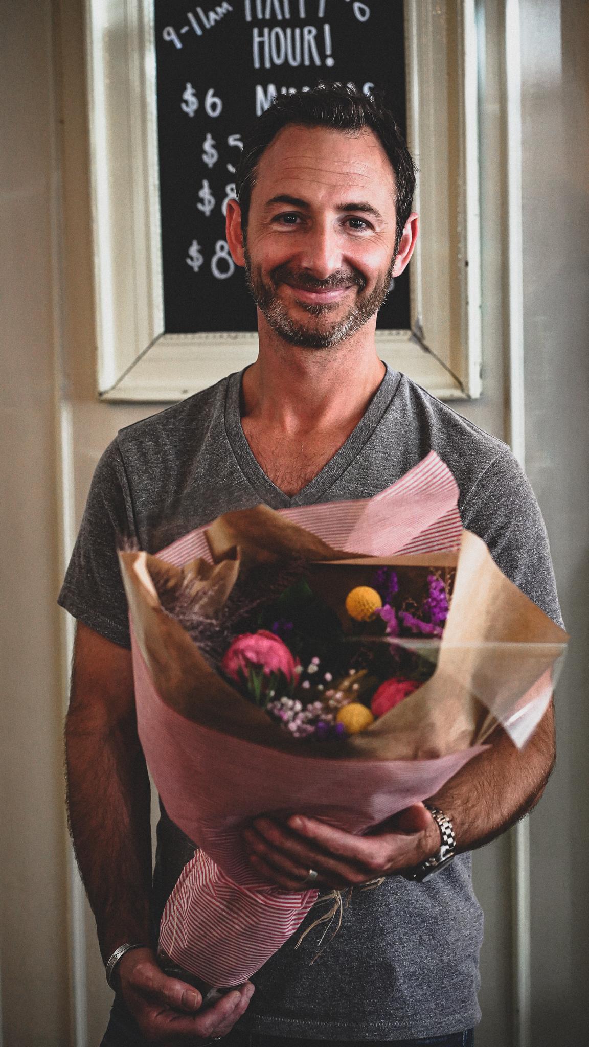 Robbie Kane, owner of Café Medina, holding a bouquet of flowers