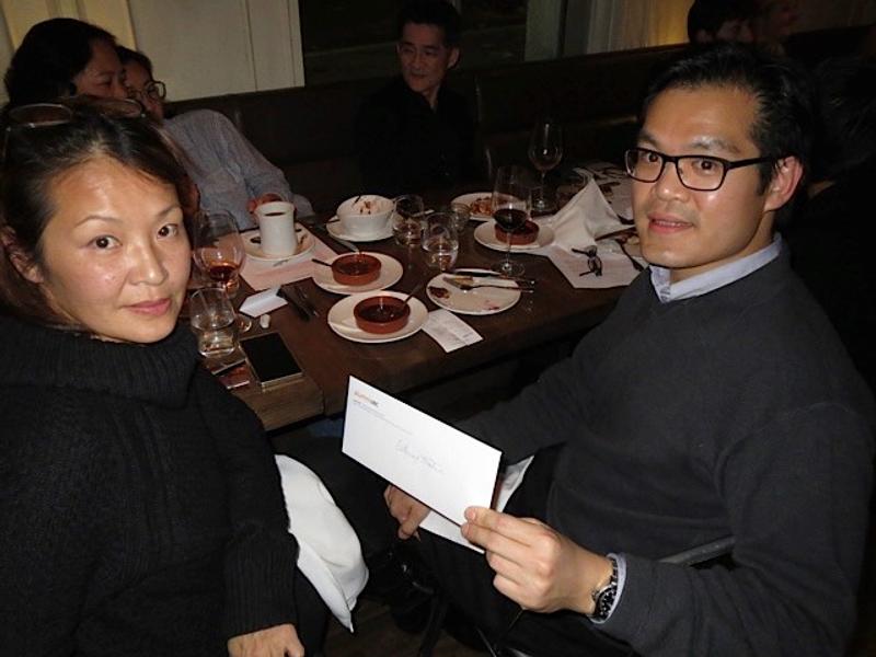 Two guests at the dinner table, holding a bid card