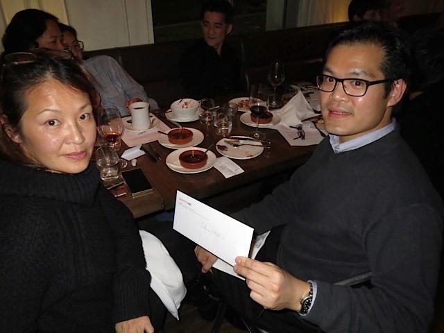 Two guests at the dinner table, holding a bid card