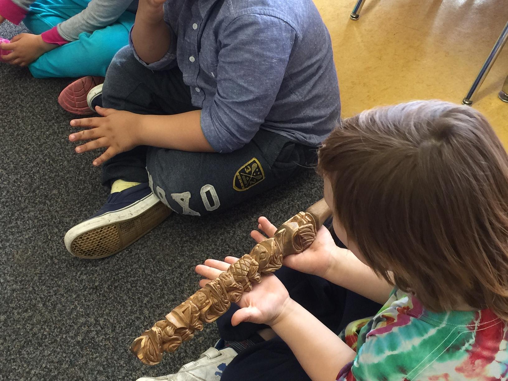 A child's hands hold a carved rattle during a workshop at the Aboriginal Open House