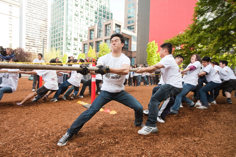 A student leans back at full stretch with his team strung out along the rope behind him