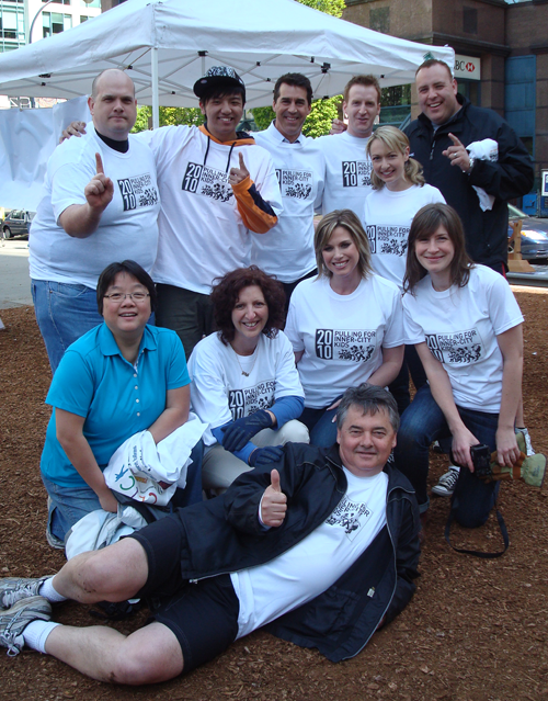 The CLICK media team in matching T-shirts pose together, one member lying across the front