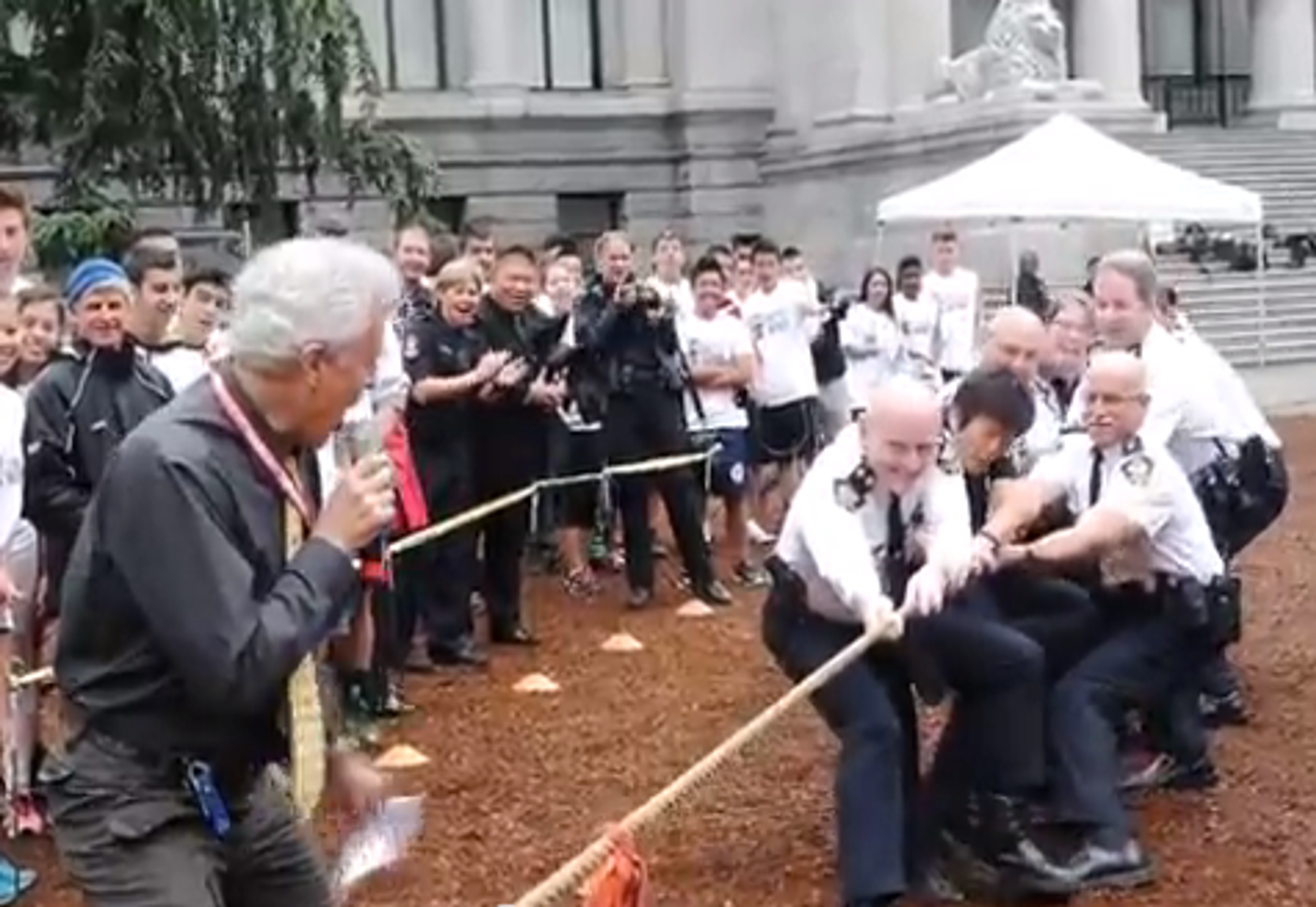 A line of officers and students straining on the tug of war rope outside the Vancouver Art Gallery