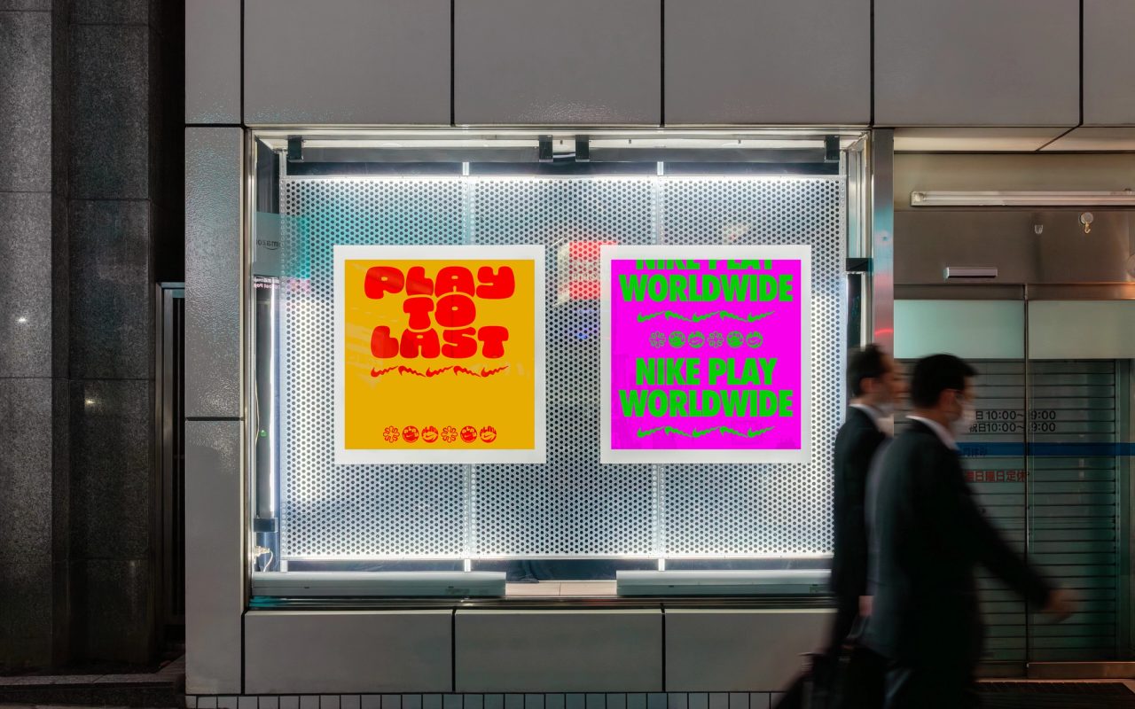 Window posters reading Play to Last and Nike Play Worldwide as two men in suits pass