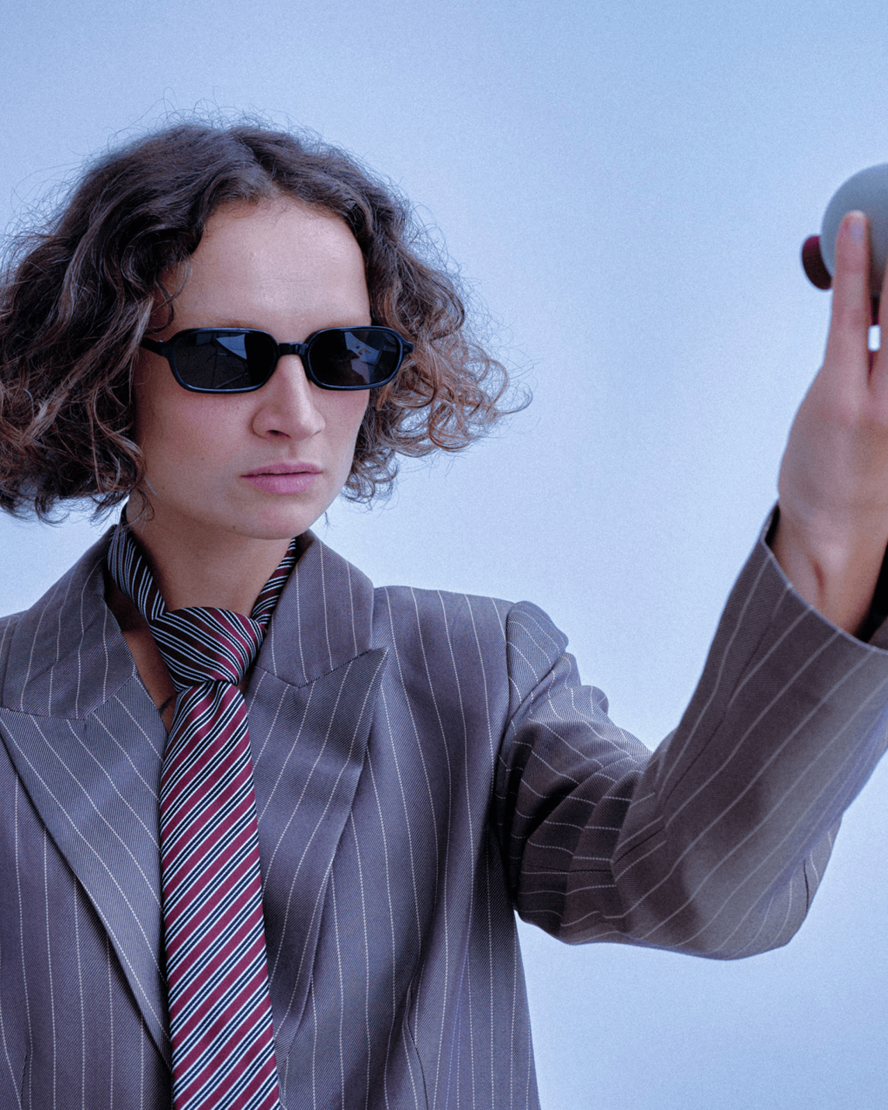 A deadpan model in a pinstripe blazer and tie