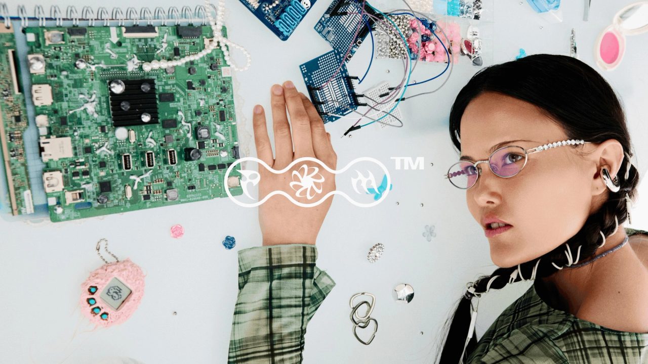 A woman in glasses among circuit boards, her open hand behind the PORTO MORTO mark