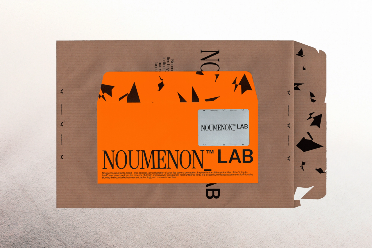 An orange NOUMENON LAB envelope on a kraft mailer, both printed with black shard shapes
