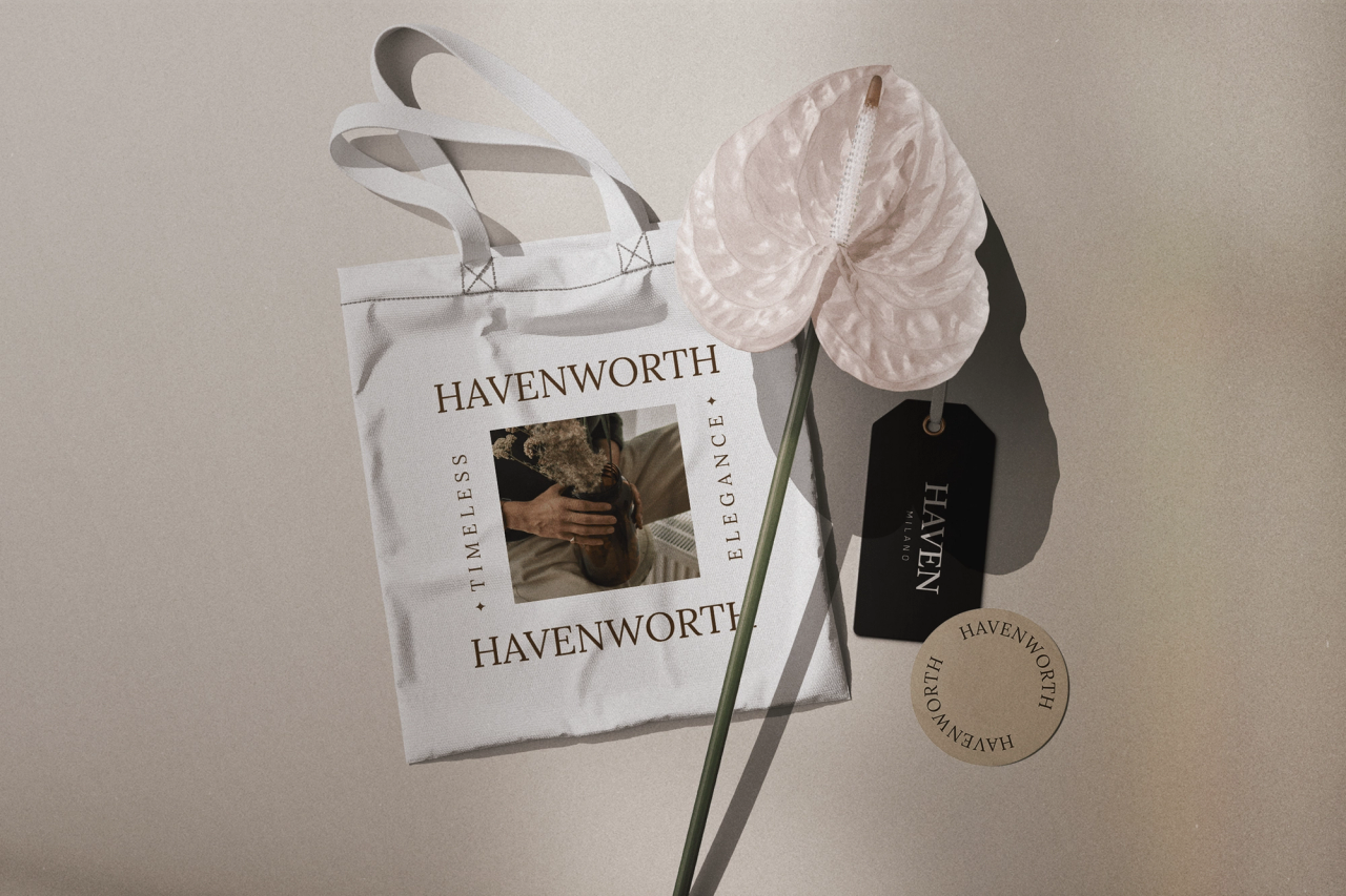 A Havenworth tote, HAVEN hang tag and round sticker beside a pale pink anthurium