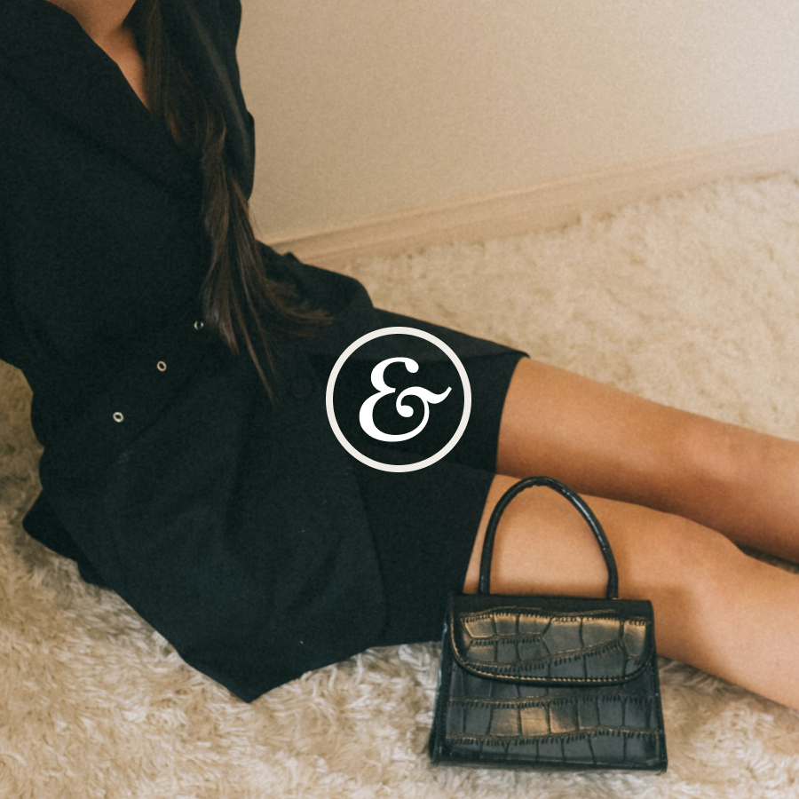 A seated model in black with a croc-embossed mini bag under the Havenworth ampersand