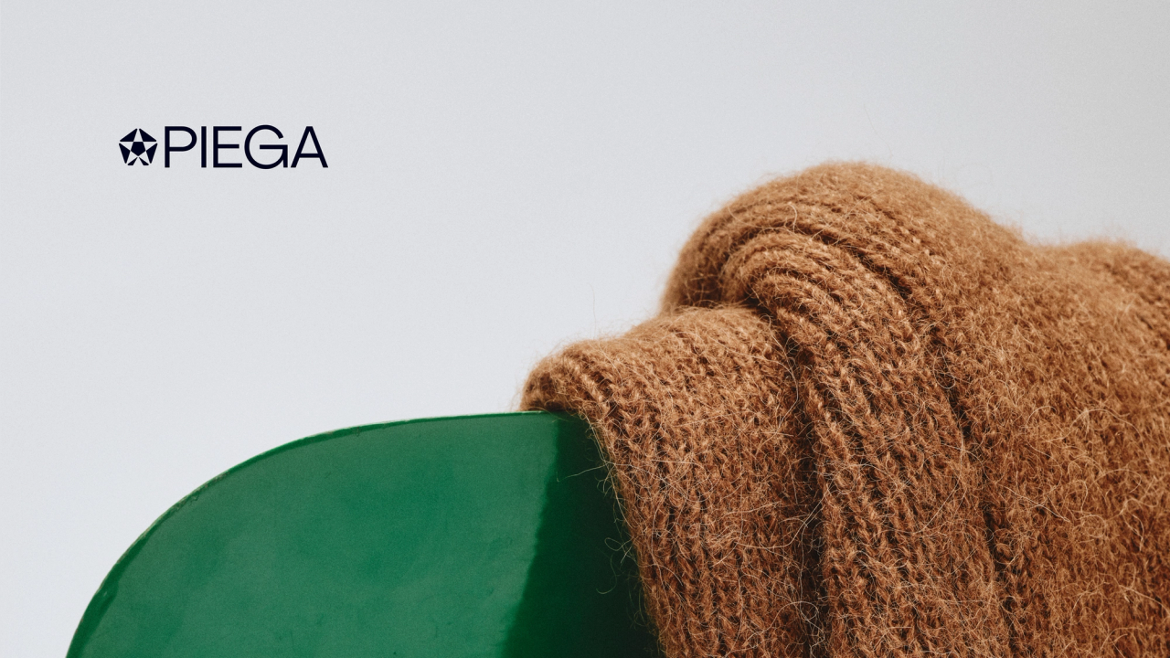 Brown knitwear draped over a green chair beside the PIEGA wordmark