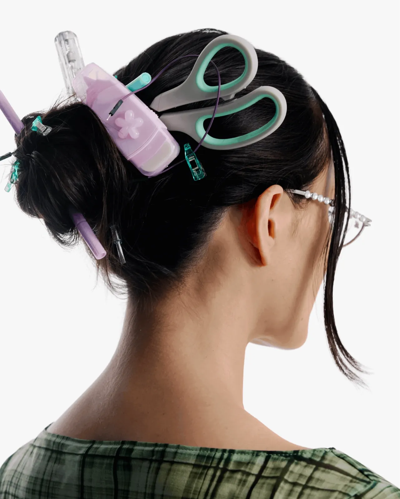 A woman from behind with scissors, clips and a lilac gadget in her bun