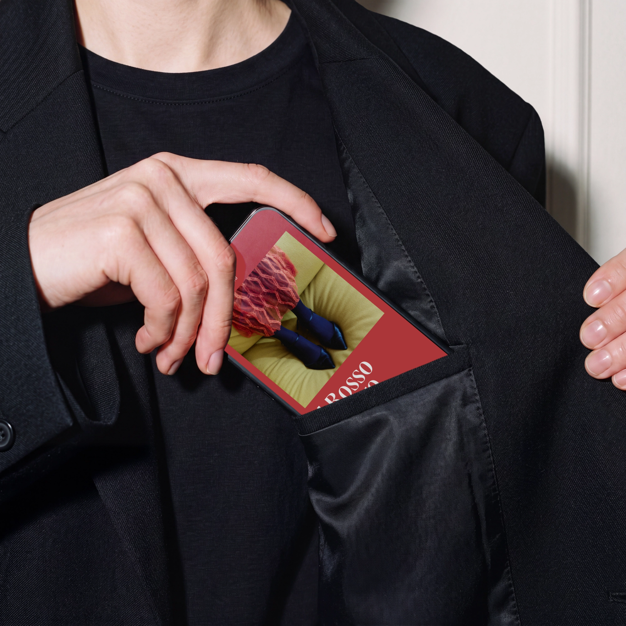 A hand tucking a phone showing red lace and blue tights into a jacket pocket