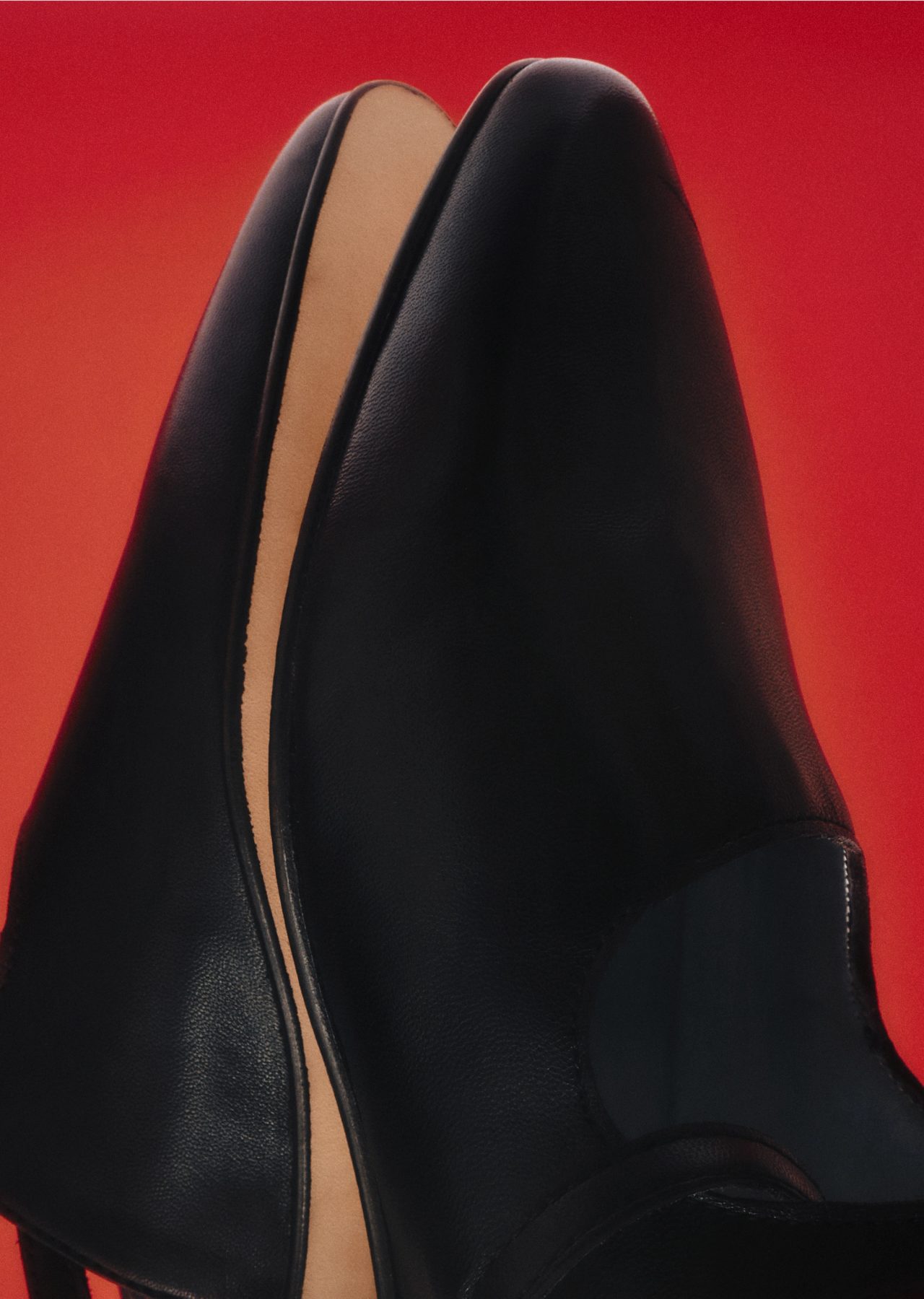 Black loafers on a red backdrop