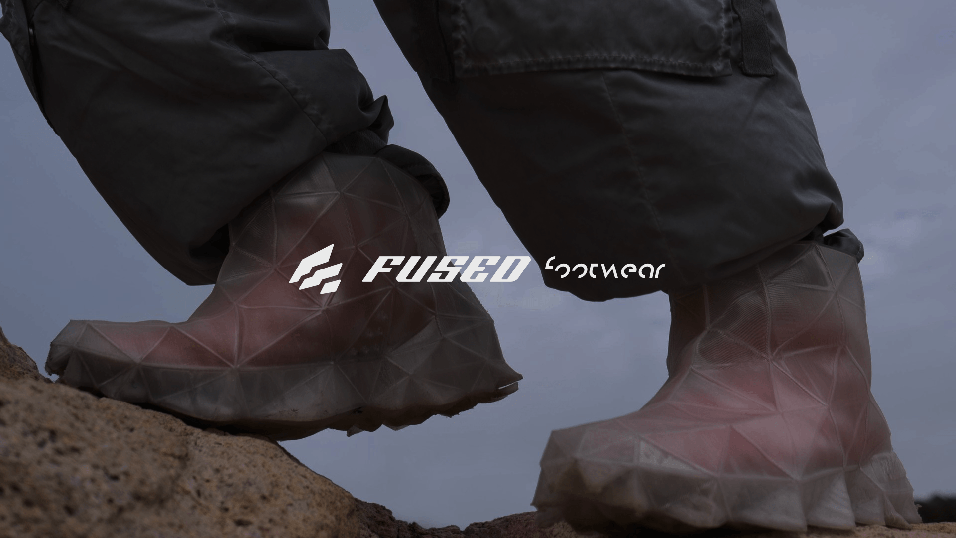 Feet in translucent 3D-printed shoes on a rock, with the Fused logo