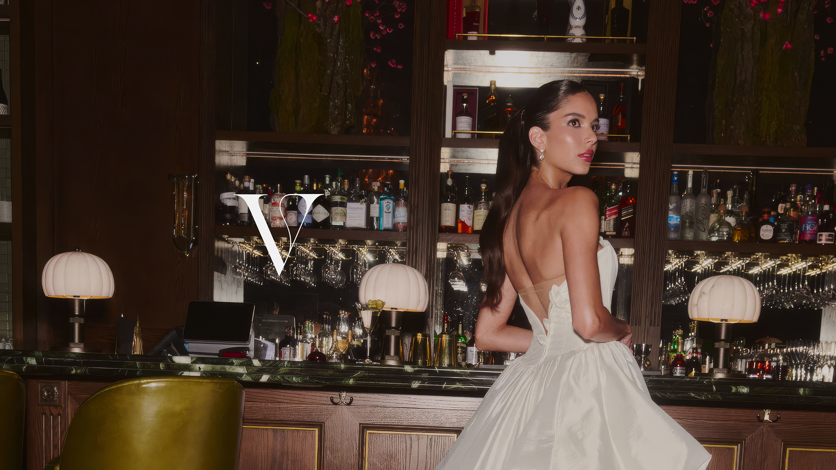 A bride at a hotel bar beside the V monogram