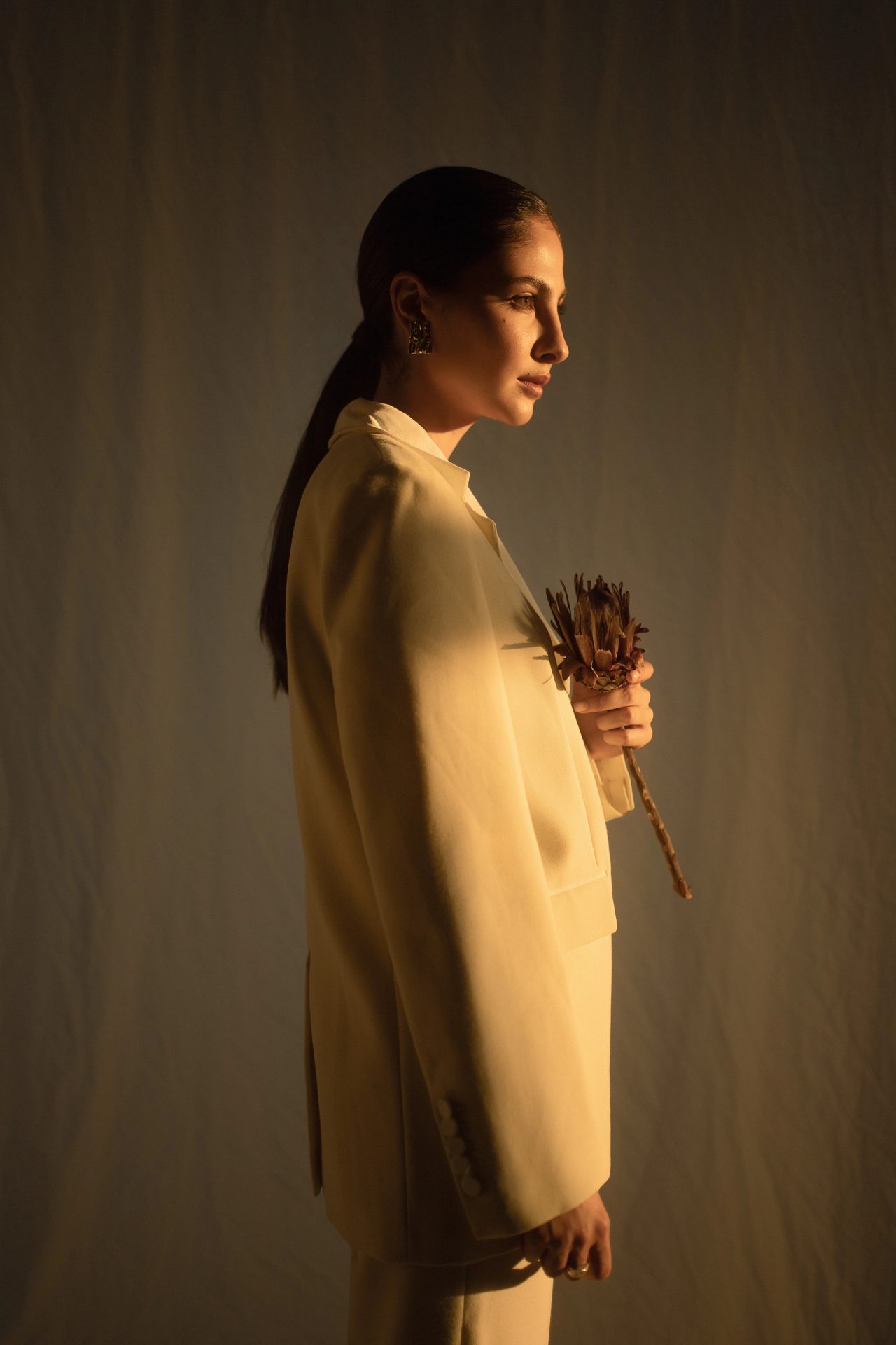 A woman in a camel suit holding dried flowers