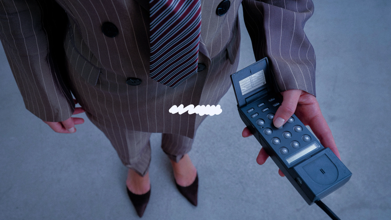 A model in a pinstripe suit holding a retro phone beside the white Inside Job scribble
