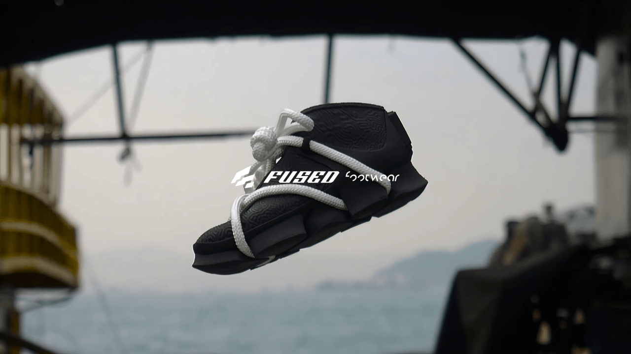 A rope-laced black shoe floating over a blurred waterfront behind the Fused logo
