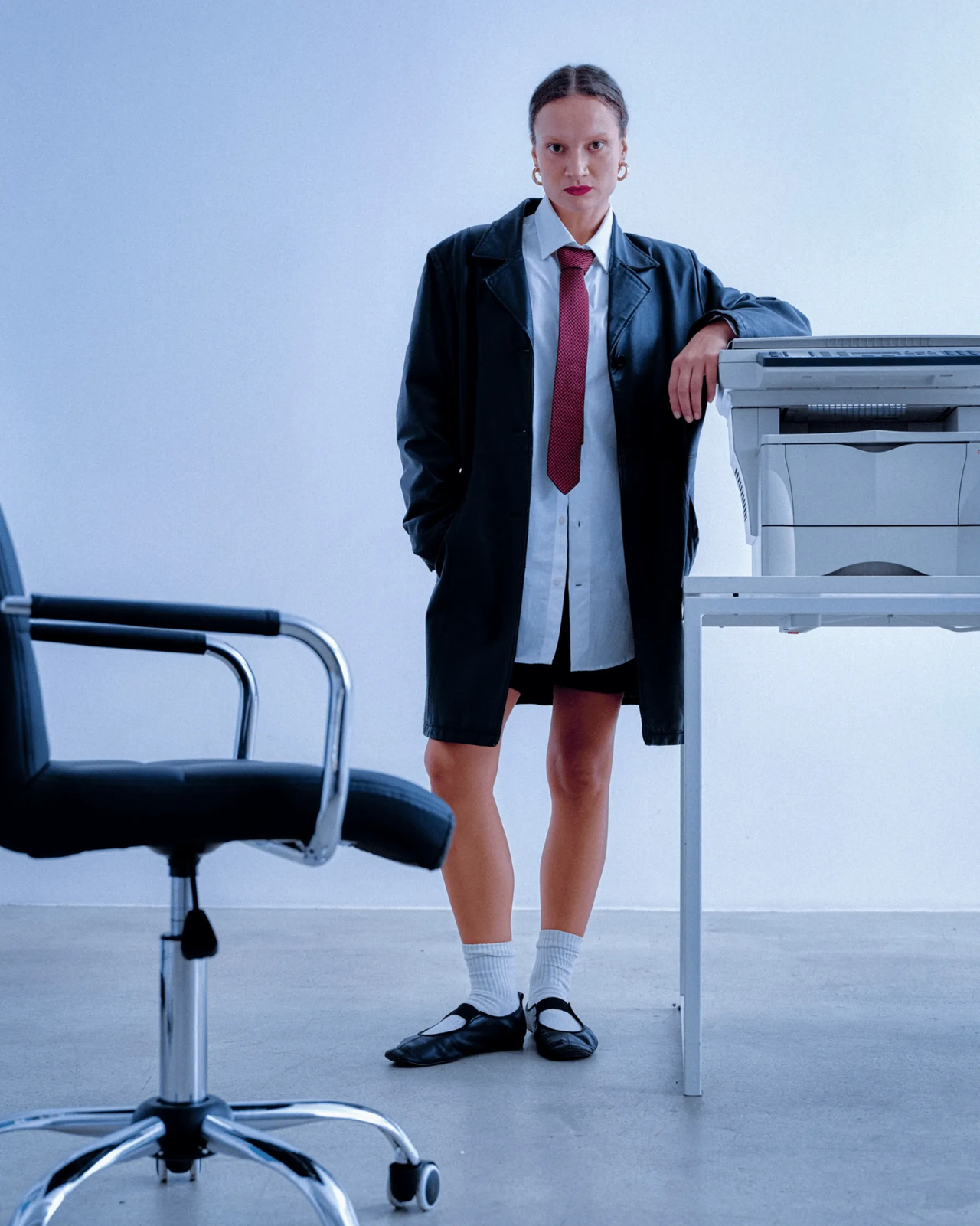 A model in a red tie leaning on a photocopier behind the Inside Job wordmark
