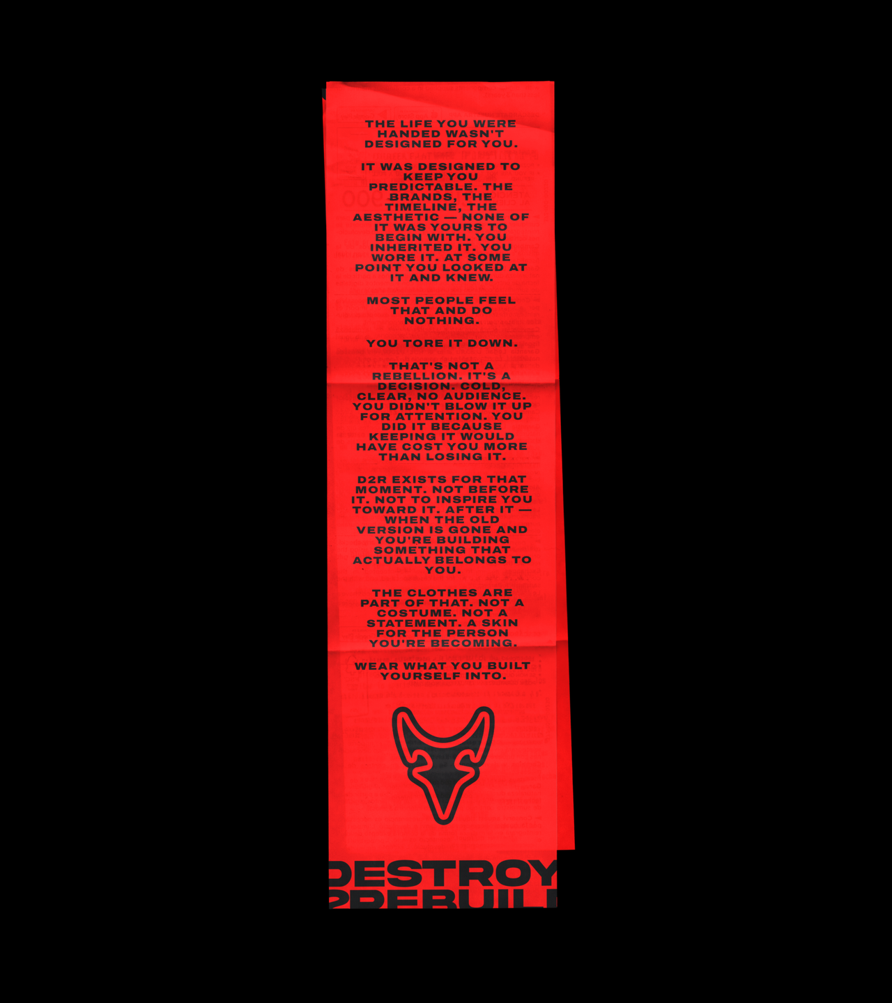 A folded red Destroy 2 Rebuild manifesto with the horned logo on black