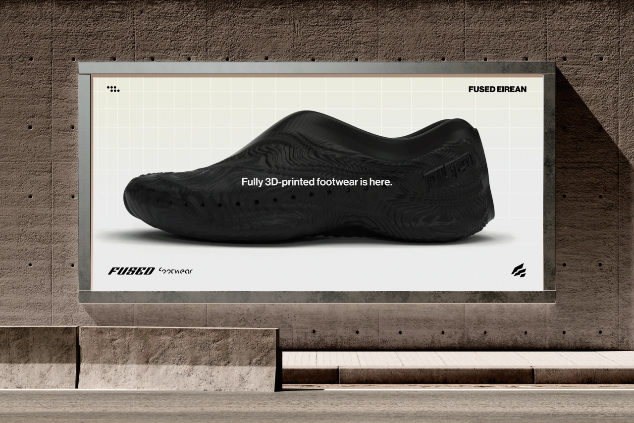 A Fused billboard on a concrete wall showing a black slip-on shoe