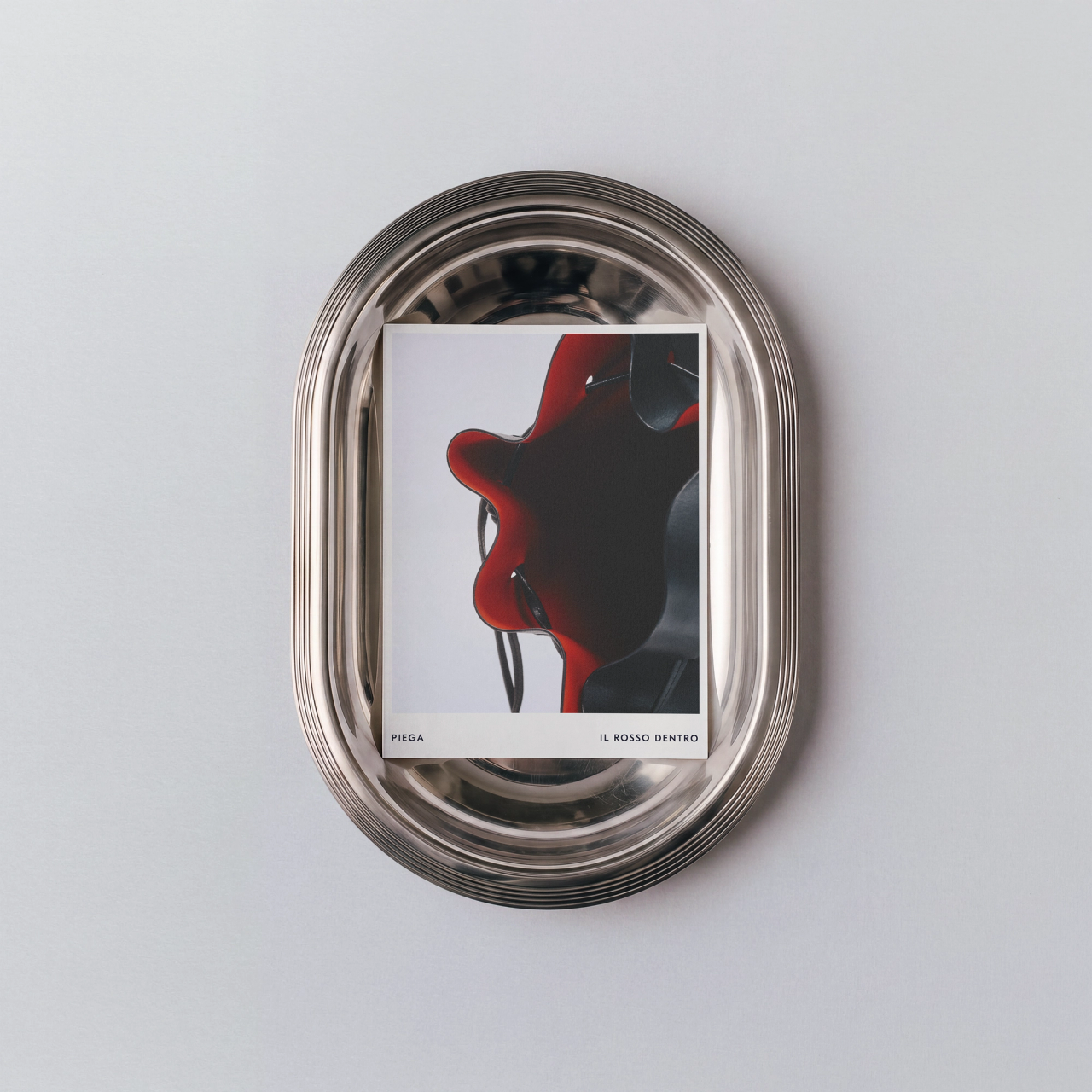 A PIEGA print captioned Il Rosso dentro in a silver oval tray